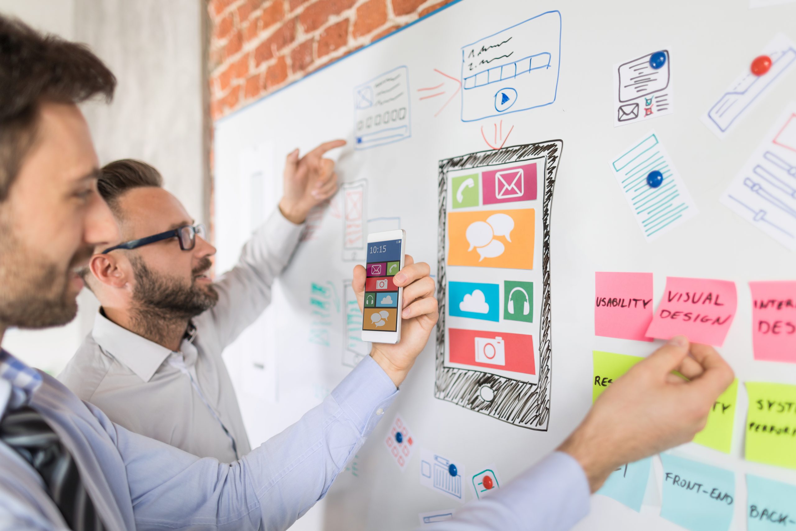 Zwei Männer stehen an einer Pinwand und erarbeiten ein Marketing-Konzept im Rahmen eines Workshops.